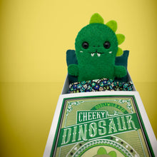 Load image into Gallery viewer, Mini green dinosaur felt toy that comes in its own bespoke matchbox. Complete with pillow and bedding - perfect for tucking in at night time. Your little friend also comes with an adoption certificate, collectible playing card, and thank you card.