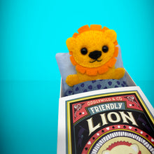 Load image into Gallery viewer, Handmade from felt this mini lion toy stands 110mm high and is perfect for your kids to that with them on their travels and adventures. Your little friend is small enough to fit in a pocket and comes with its own matchbox and bedding. 