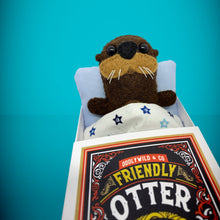 Load image into Gallery viewer, Handmade from felt this mini brown otter toy stands 110mm high and is perfect for your kids to that with them on their travels and adventures. Your little friend is small enough to fit in a pocket and comes with its own matchbox and bedding. 