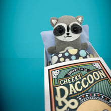Load image into Gallery viewer, Handmade from felt this mini grey raccoon toy stands 110mm high and is perfect for your kids to that with them on their travels and adventures. Your little friend is small enough to fit in a pocket and comes with its own matchbox and bedding