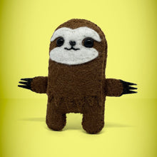 Load image into Gallery viewer, The front view of our handmade felt mini sloth toy stands 110mm high and is perfect for your kids to that with them on their adventures. Your little friend is small enough to fit in a pocket and comes with its own matchbox and bedding.